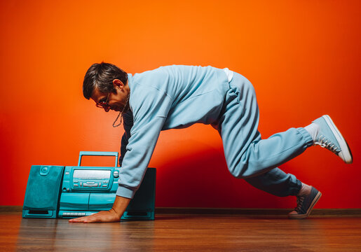 Breakdancer in blue tracksuit with boombox in retro orange room