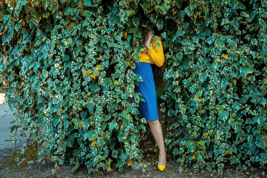 Housewife in retro style hiding in a green ivy wall outdoors