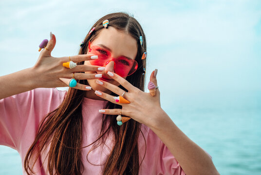 Smiling girl with pink sunglasses and playful jewelry by the sea