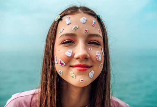 Smiling girl wearing kawaii stickers and pink shirt by the sea