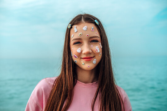 Smiling girl with kawaii stickers on face by the sea