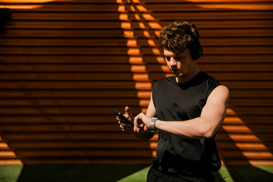 Athlete checking smartwatch and smartphone outdoor during training