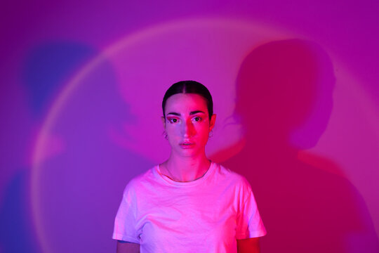 Young woman in neon lighting against gradient background
