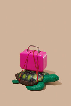 Plastic toy turtle carrying a pink suitcase tied with red string