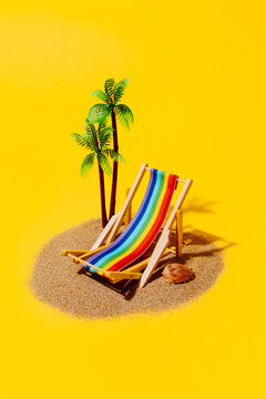 Miniature rainbow deck chair on sand for LGBTQ pride summer escape