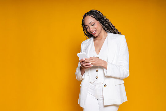Entrepreneur in white blazer texting on cellphone in studio