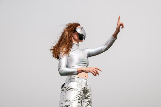 Interacting with VR glasses in futuristic metallic clothes outdoors