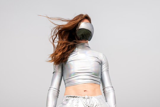 Red-haired model in futuristic metalized clothes and VR glasses