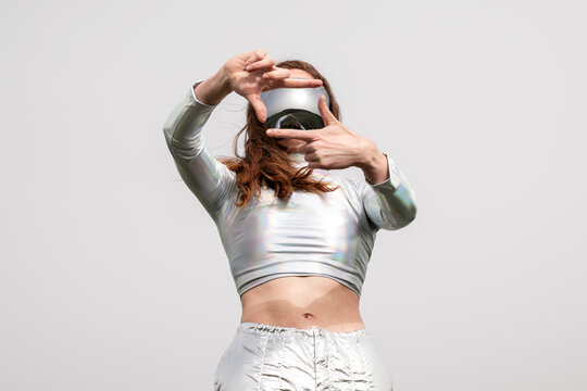 Model with red hair in metallic clothing framing shot with VR visor