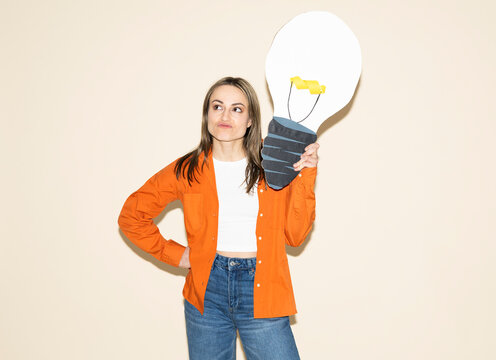 Creative businesswoman holding paper light bulb indoors
