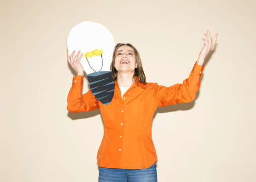 Woman holding a paper light bulb indoors for creativity and brainstorming