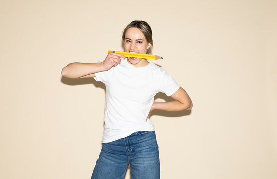 Creative designer biting an oversized yellow pencil in studio