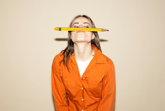 Designer balancing oversized pencil on face during brainstorming