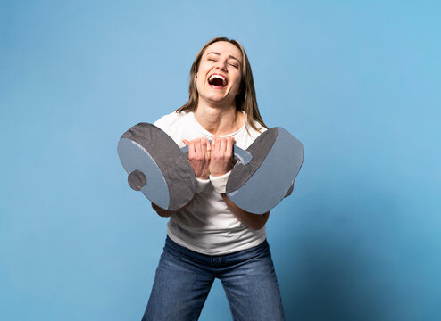 Woman laughing while holding an oversized fake paper dumbbell