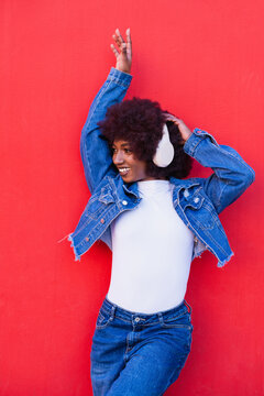 Smiling dancer listening to music on red background