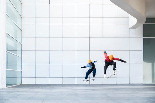 Synchronized skateboard trick against modern minimalist wall
