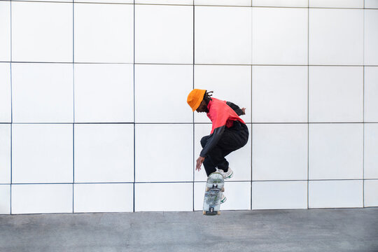 Skateboarder jumping midair against minimal white wall in Barcelona
