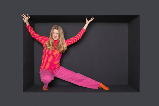 Teenage girl with arms raised stretching against black background
