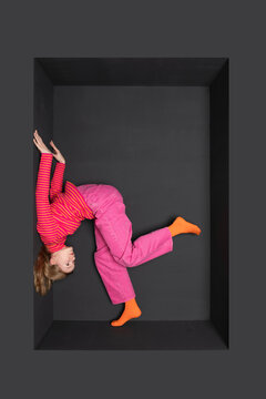 Girl upside down in alcove against black background