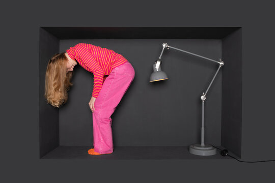 Blond teenager standing in front of electric lamp over black background