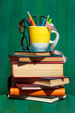 Colorful book stack with a pencil cup and eyeglasses