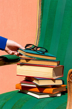 Hand reaching for book and eyeglasses on a colorful armchair