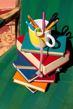 Colorful stack of books and a mug on a green armchair