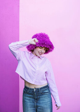 Redhead smiling indoors in fluffy purple hat and shirt