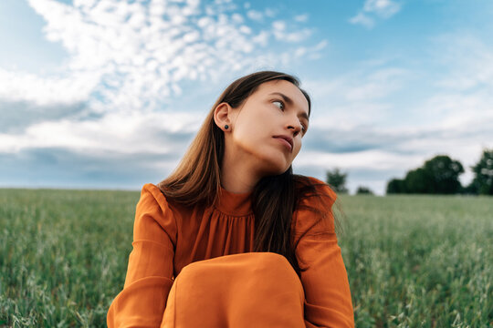 Thoughtful woman sitting in field of corn