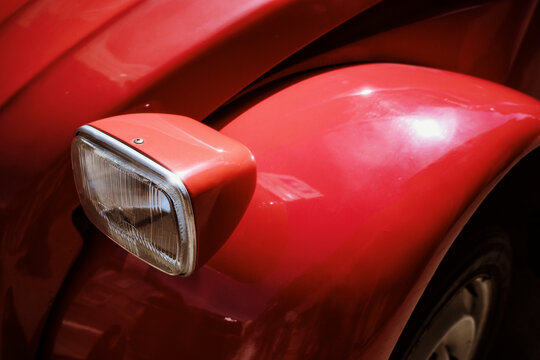 Close up of a vintage red car headlight on a sunny street