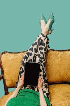 Person holding tablet while relaxing on vintage sofa in the evening