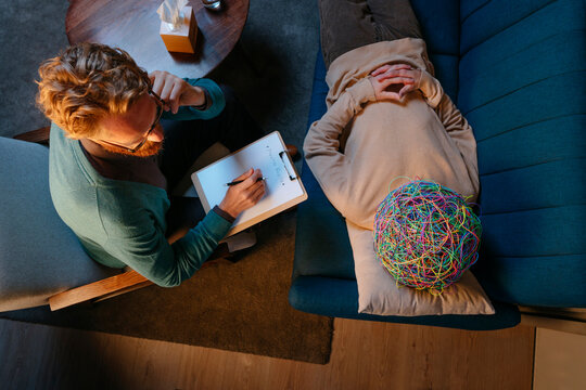 Patient with mask of chaos lying down on psychiatrist's couch