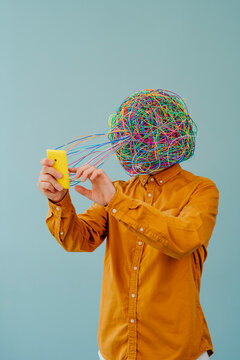 Man with chaotic thoughts using smart phone against blue background