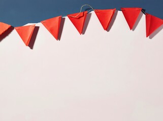 Obraz premium Red bunting flags on a string hanging over a light surface with copy space for autumn festival announcements, party planning blogs and festive event invitations