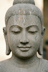 Obraz premium Stone Buddha statue head close up with serene expression and closed eyes for spiritual meditation, wellness center interior design and spa branding materials