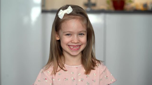 Portrait of happy toothless girl looks at camera and laughs. Funny child smiles. Baby milk teeth change