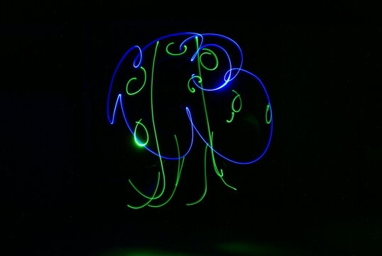 Photographie de light painting &agrave; longue exposition, lignes sinueuses, dessins et textes couleurs n&eacute;ons &eacute;clatant sur fond noir. 