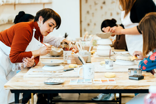 People enjoying creative ceramic painting workshop, making handmade artisanal pottery