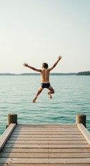Fototapeta premium Calm blue lake water with a boy jumping from a wooden dock for youth adventure brands, summer camp promotion and travel advertising featuring copy space