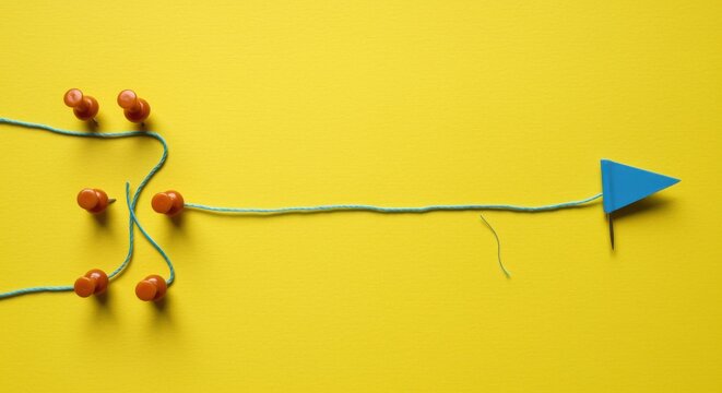 Bright yellow textured background with blue thread connecting orange push pins to a flag showing progress for startup milestone tracking, strategic planning and logic puzzles
