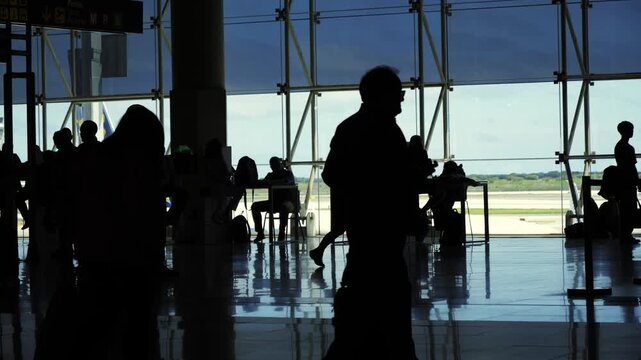 Silhouette of passengers with suitcases in the airport terminal, people-passengers scurry around the terminal to different gates. High quality 4k footage