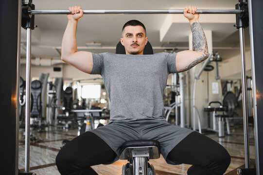Young man training fitness on smith machine in gym