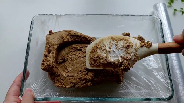The man puts the halva into the mold with a spatula, preparing it. The process of making homemade halva. Sunflower halva.