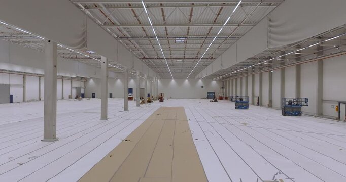 Interior view of a large empty warehouse with white walls and polished concrete floors