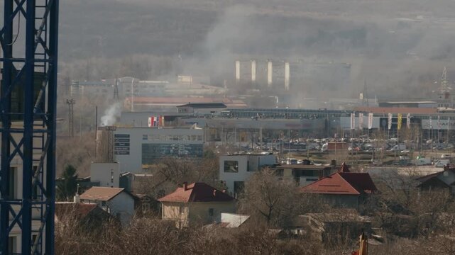Distant view of a city experiencing a fire accident with thick smoke rising from buildings, showcasing an emergency urban disaster and significant air pollution over the neighborhood. timelapse