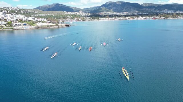Aerial View of Professional Rowing Teams Competing in a Regatta near Scenic Coastal Town with Mountains. High quality 4k footage