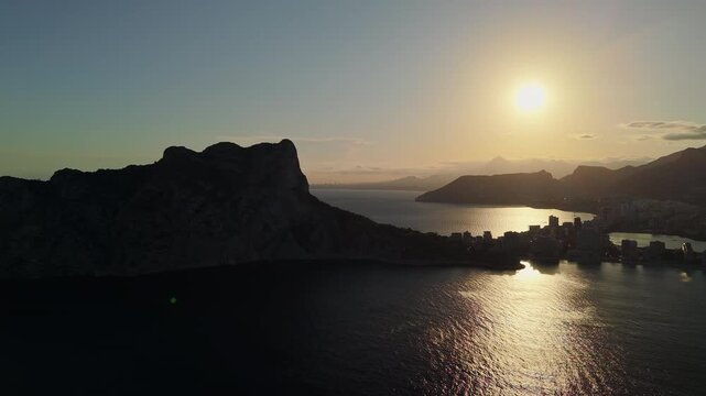 Aerial sunrise over Penon de Ifach silhouette and Calpe bay coastline Spain