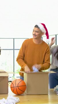 Sorting group folding donations on wood table by window, with cardboard boxes and festive headwear