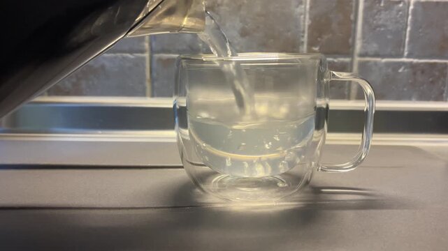 Water with sediment, scale, cloudy water, sediment Static shot of glass mug being filled with hot water on kitchen sink counter with tiled backsplash