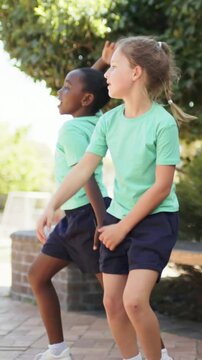 Vertical video: Stepping from behind bench, two students practicing moves at school in mint shirts